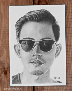 Portret w galerii ołówkiem przedstawiający chłopaka w przeciwsłonecznych okularach. Wykonany na białym papierze formatu A5.