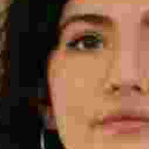 Obraz przedstawia zbliżenie twarzy tak, aby widoczne były kąciki ust i oczu niezbędne do wykonania portretu ze zdjęcia. Na zdjęciu widać, że elementy te jak i całe zdjęcie po powiększeniu są niewyraźne. Jest to przykład zdjęcia o niskiej jakości. Powiększone zostało zdjęcie wykonane z daleka.