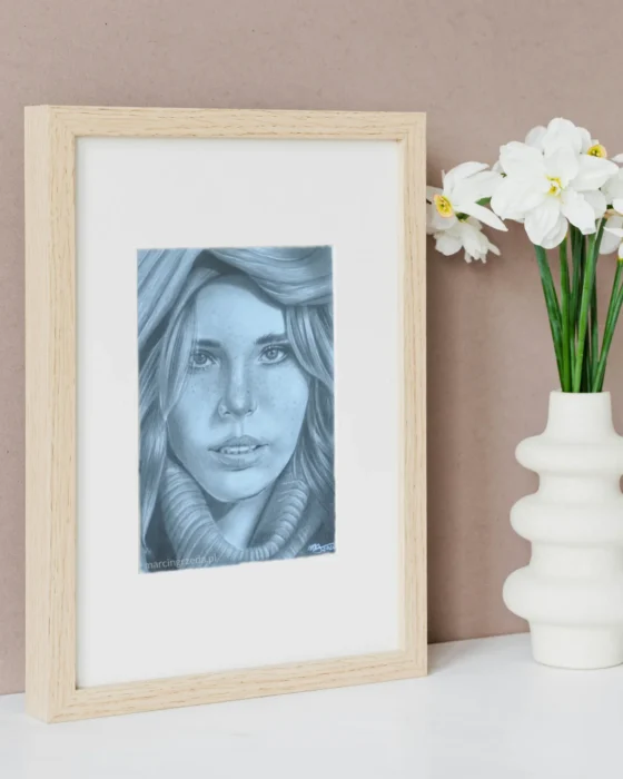 Portret dziewczyny w golfie narysowany ołówkiem na formacie A5. Portret jest oprawiony w jasną drewnianą ramkę z passe-partout.