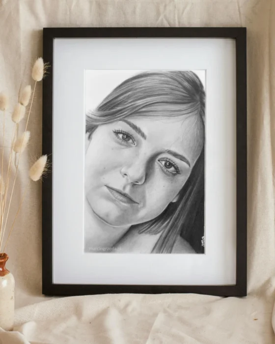 Portret dziewczyny wykonany ołówkiem na formacie A5. Portret jest oprawiony w ciemną ramkę z passe-partout.