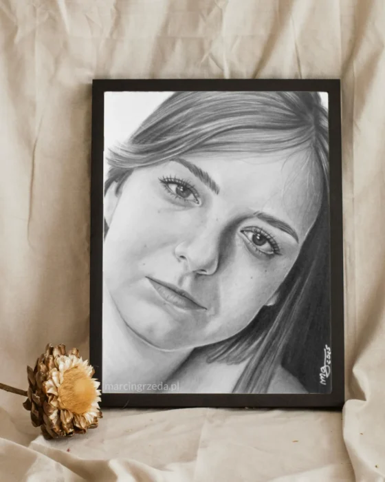 Portret dziewczyny wykonany ołówkiem i oprawiony w ciemną ramkę. Portret jest formatu A5.