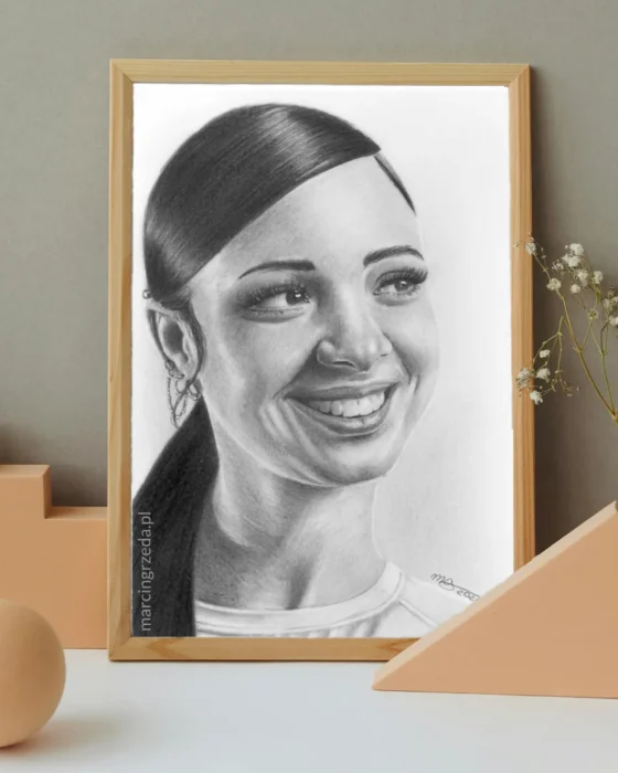 Portret uśmiechniętej kobiety z kucykiem. Portret jest na formacie A5 i jest oprawiony w jasną drewnianą ramkę.