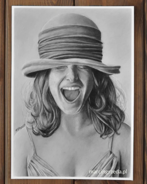 Portret ołówkiem przedstawiający śmiejącą się kobietę z zamkniętymi oczami. Cechą charakterystyczną widoczną na rysunku jest kapelusz mocno naciągnięty na głowę w taki sposób, że nachodzi na oczy. Dziewczyna z tego powodu mocno się uśmiecha.