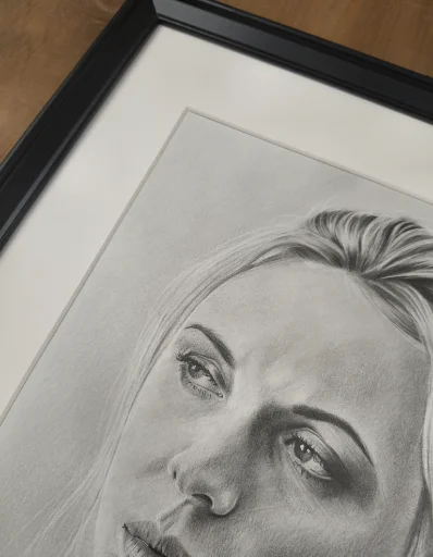 Zdjęcie przedstawia część oprawionego portretu z passe-partout. Głównym celem zdjęcia jest pokazanie przestrzeni pomiędzy rysunkiem a szybą ramki.