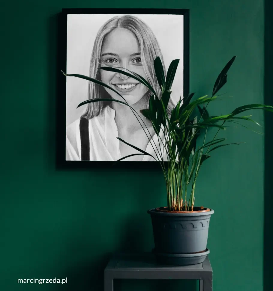 Portret pięknej dziewczyny wiszący w ciemnej ramie na ścianie. Przed portretem stoi kwiatek w doniczce, który częściowo zasłania portret. Portret pięknie się komponuje z wystrojem wnętrza.